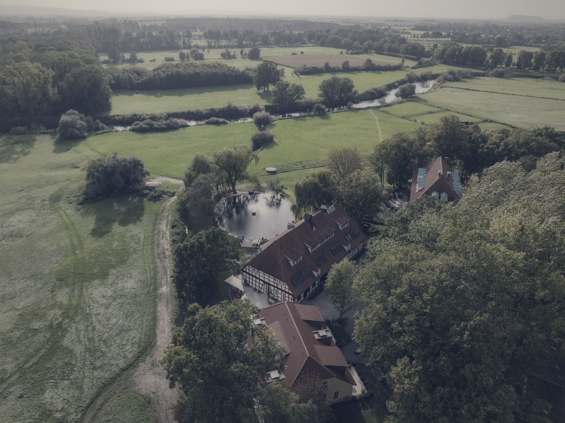Das Anwesen an der Leine aus der Luft: Schloss, Fachwerkbau, Teich, Park und Wiesen